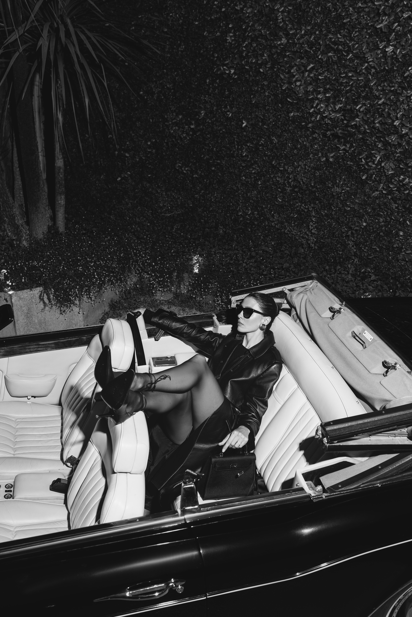 Cinematic black and white fashion campaign retouching featuring leather apparel and vintage luxury car