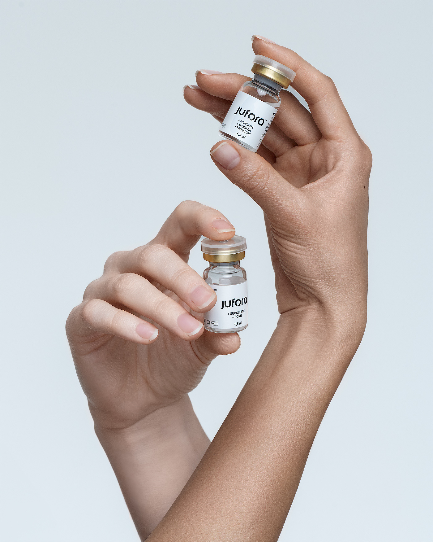 Skincare product retouching for cosmetic brands: Jufora vials in hand, glass, skin and label for advertising packshots